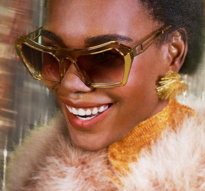 Model wearing women's designer oversized tan and gold sunglasses