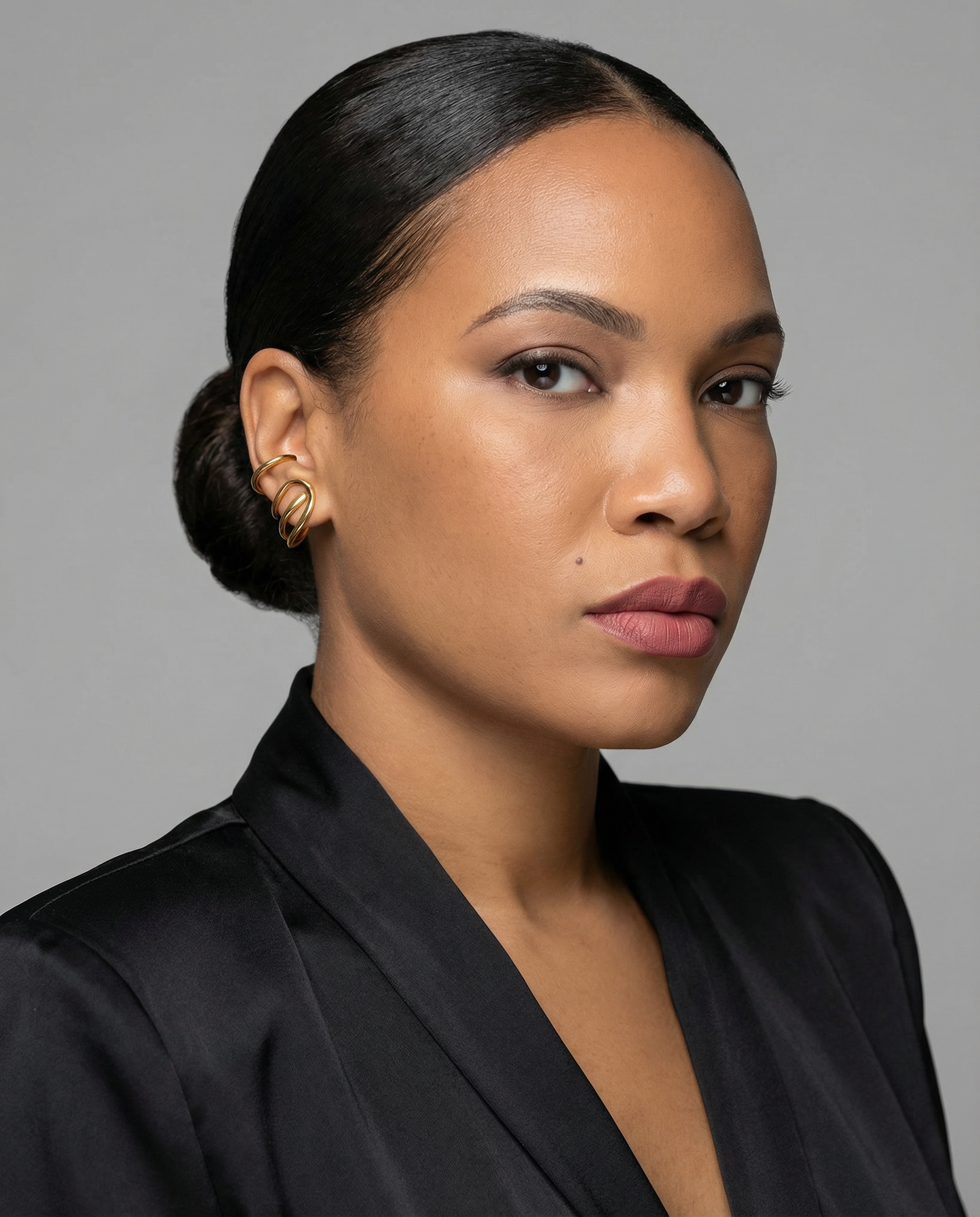Woman with styled hair wearing a black top against a gray background